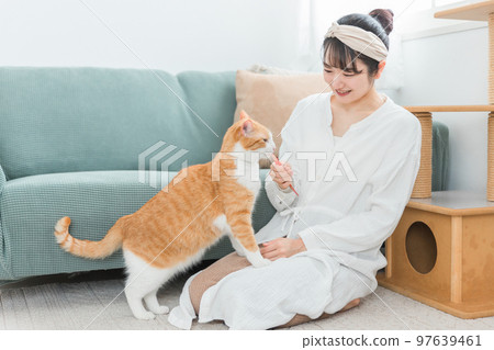Japanese woman giving a snack to a cat at a house/cat cafe (bait) Japanese woman giving a snack to a cat at a house/cat cafe (bait) 97639461