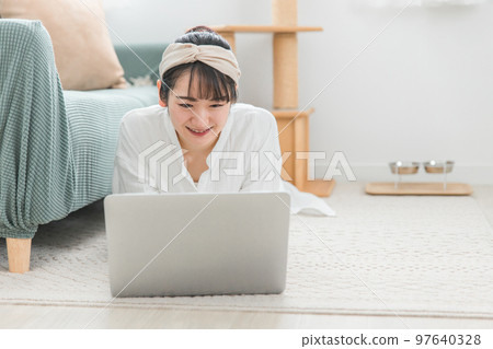 Asian woman watching a laptop while relaxing at home (cat lover, e-book, manga, video) 97640328