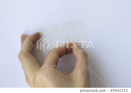 Round patches for acne and wrinkles on the hands on a white background. Acne and wrinkle patches for facial rejuvenation. Cleansing cosmetology. 97642153