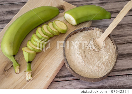 Flour of green bananas on a table next to a cutting board with a cut banana into rings 97642224