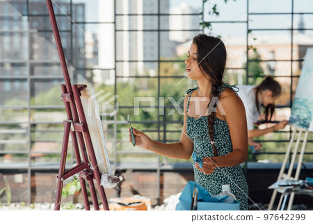 Young woman artist paints with a spatula on the canvas 97642299