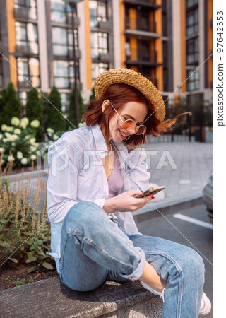 Young lady sitting stairs typing device outside urban city street 97642353