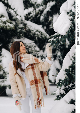 Portrait of a girl with long hair in mittens in a winter forest . Snowy winter Portrait of a girl with long hair in mittens in a winter forest . Snowy winter 97642832