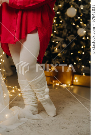 close-up of women's legs, dressed in warm leggings, standing near the Christmas tree 97642835