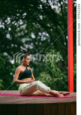 A young woman in doing yoga in the yard A young woman in doing yoga in the yard 97642898