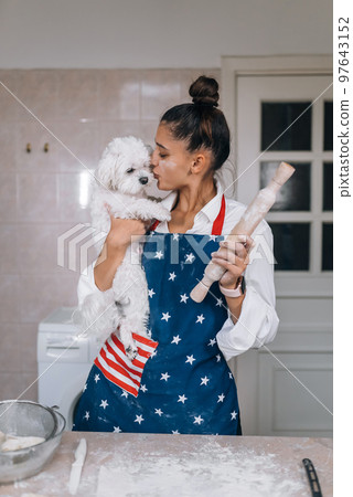 Cheerful woman with a rolling pin and white Maltese dog Cheerful woman with a rolling pin and white Maltese dog 97643152