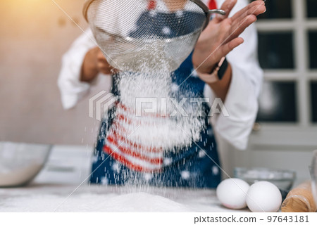 Woman sifting flour through sieve. Selective focus. 97643181