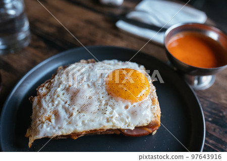 Toast with cheese and sausage covered with fried egg 97643916