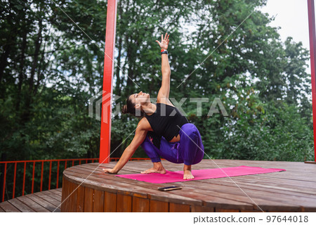 A young woman in doing yoga in the yard 97644018