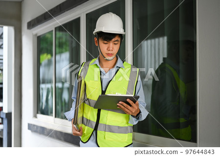 Image of engineer man looking at clipping board and checking building construction progress, working at construction site Image of engineer man looking at clipping board and checking building construction progress, working at construction site 97644843