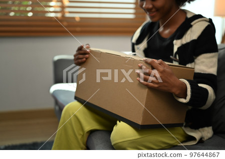 An excited woman unpacks a delivered order. Online shopping for