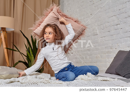 Portrait of adorable emotional little girl on the bed, with pillow 97645447