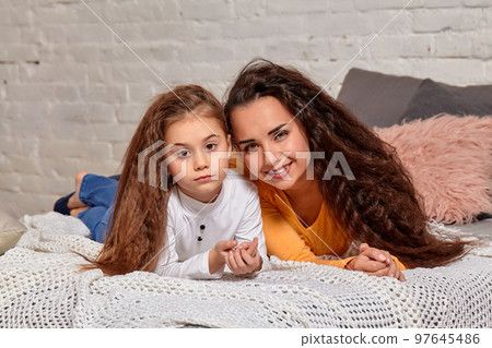 Love of young mother and daughter. They lie on the bed at home and have fun Love of young mother and daughter. They lie on the bed at home and have fun 97645486