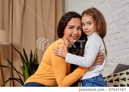 Love of young mother and daughter. They sit on the bed at home and have fun Love of young mother and daughter. They sit on the bed at home and have fun 97645567