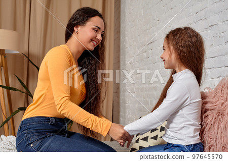 Love of young mother and daughter. They sit on the bed at home and have fun 97645570