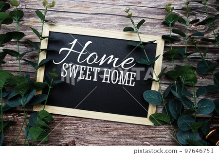Home Sweet Home typography text written on wooden blackboard with green eucalyptus decoration on wooden background 97646751