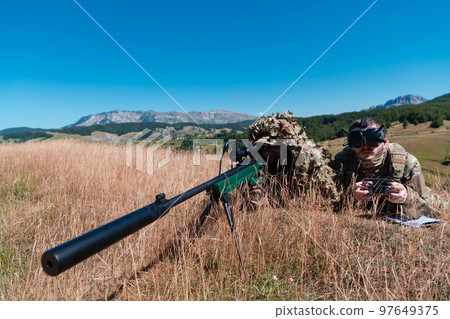 Sniper soldier assisted by an assistant to observe the area to be targeted with modern warfare tactical virtual reality goggles aerial drone military technology. Sniper soldier assisted by an assistant to observe the area to be targeted with modern warfare tactical virtual reality goggles aerial drone military technology. 97649375