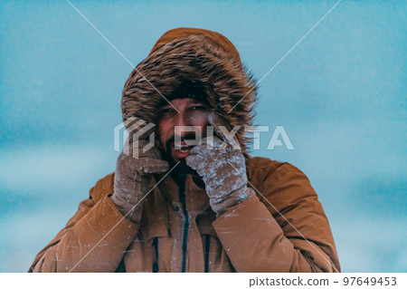 Headshot photo of a man in a cold snowy area wearing a thick brown winter jacket and gloves. Life in cold regions of the country. Headshot photo of a man in a cold snowy area wearing a thick brown winter jacket and gloves. Life in cold regions of the country. 97649453