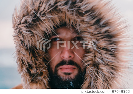 Headshot photo of a man in a cold snowy area wearing a thick brown winter jacket and gloves. Life in cold regions of the country. Headshot photo of a man in a cold snowy area wearing a thick brown winter jacket and gloves. Life in cold regions of the country. 97649563