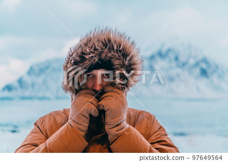 Headshot photo of a man in a cold snowy area wearing a thick brown winter jacket and gloves. Life in cold regions of the country. Headshot photo of a man in a cold snowy area wearing a thick brown winter jacket and gloves. Life in cold regions of the country. 97649564