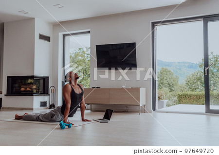 Training At Home. Sporty man doing training while watching online tutorial on laptop, exercising in living room, free space Training At Home. Sporty man doing training while watching online tutorial on laptop, exercising in living room, free space 97649720