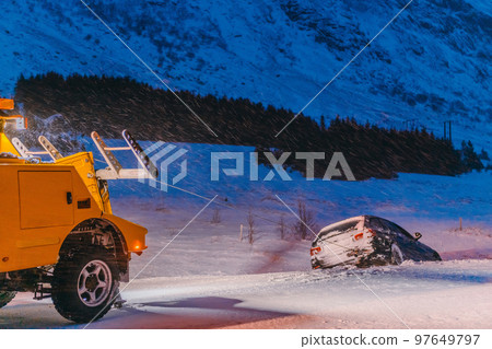 The roadside assistance service pulling the car out of the canal. An incident on a frozen Scandinavian road. The roadside assistance service pulling the car out of the canal. An incident on a frozen Scandinavian road. 97649797