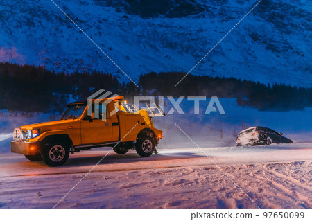 The roadside assistance service pulling the car out of the canal. An incident on a frozen Scandinavian road. 97650099