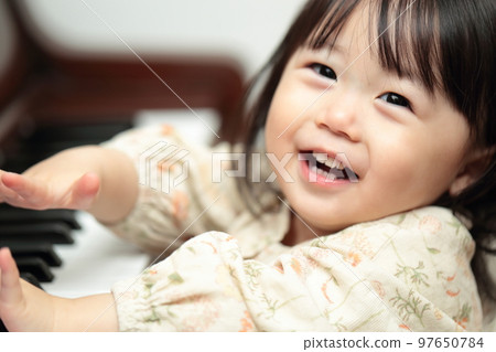 1 year old girl playing upright piano 97650784
