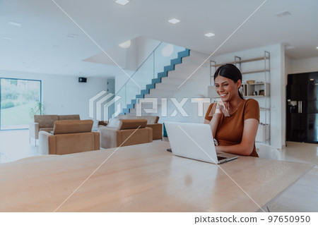 Woman sitting in living room using laptop look at cam talk by video call with business friend relatives, head shot. Job interview answering questions. Woman sitting in living room using laptop look at cam talk by video call with business friend relatives, head shot. Job interview answering questions. 97650950