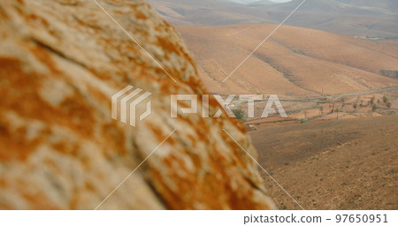 Desert landscape near Mirador de Las Penitas and Montana de Melindraga at sunset, Fuerteventura island, Spain. Slow motion. Close up. Terrain from the top of the mountain. Hiking climb. 97650951