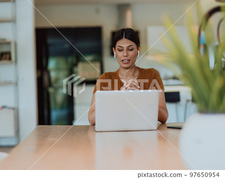 Woman sitting in living room using laptop look at cam talk by video call with business friend relatives, head shot. Job interview answering questions. Woman sitting in living room using laptop look at cam talk by video call with business friend relatives, head shot. Job interview answering questions. 97650954