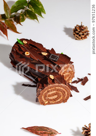 Sliced chocolate cake roll with buttercream and hazelnuts on white background 97651236
