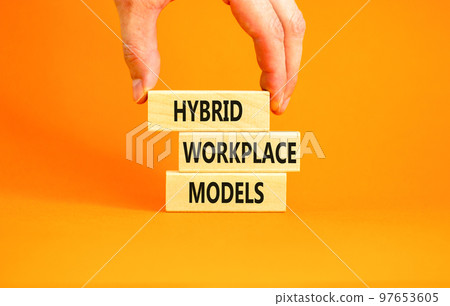 Hybrid workplace models symbol. Concept words Hybrid workplace models on wooden blocks. Businessman hand. Beautiful orange background. Business hybrid workplace models quote concept. Copy space Hybrid workplace models symbol. Concept words Hybrid workplace models on wooden blocks. Businessman hand. Beautiful orange background. Business hybrid workplace models quote concept. Copy space 97653605