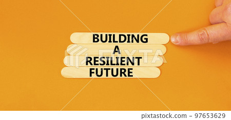 Building a resilient future symbol. Concept word Building a resilient future on wooden sticks. Beautiful orange table orange background. Business and building a resilient future concept. Copy space. 97653629