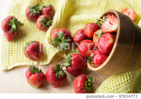 Strawberries in a wooden bowl next to a yellow towel Strawberries in a wooden bowl next to a yellow towel 97654772