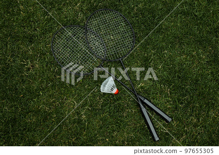 Badminton rackets and shuttlecock on green grass Badminton rackets and shuttlecock on green grass 97655305