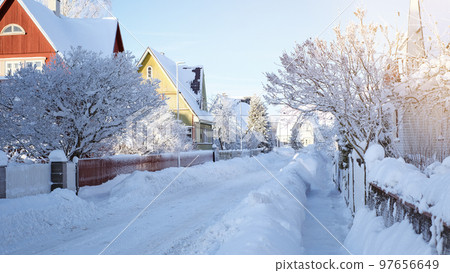 Winter fairy-tale landscape on the street with houses with a triangular roof and roads covered with a lot of snow Winter fairy-tale landscape on the street with houses with a triangular roof and roads covered with a lot of snow 97656649