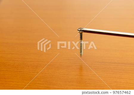 A metal screw attached to the tip of a screwdriver A metal screw attached to the tip of a screwdriver 97657462