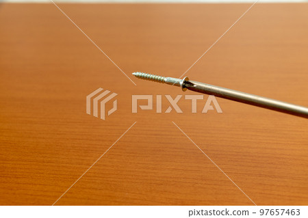 A metal screw magnetically attached to the tip of a screwdriver 97657463