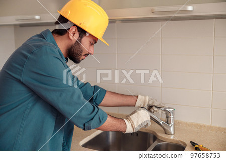 Male plumber repair sink faucet at customer kitchen. Good quality plumbing company service 97658753