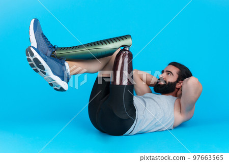 Man with a leg prosthesis doing abdominal crunches 97663565