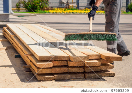 Working brush cleans wooden boards from sawdust and chips. Authentic workflow. Carpenter prepares Working brush cleans wooden boards from sawdust and chips. Authentic workflow. Carpenter prepares 97665209