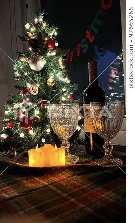 Christmas night tree, wine glasses, candles and checkered tablecloth in a warm atmosphere 97665268