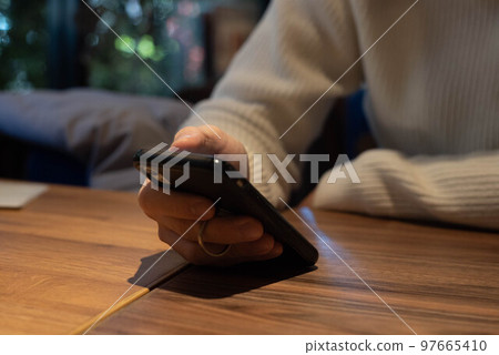 On holiday, a man relaxingly checking his smartphone at a cafe with an adult atmosphere 97665410