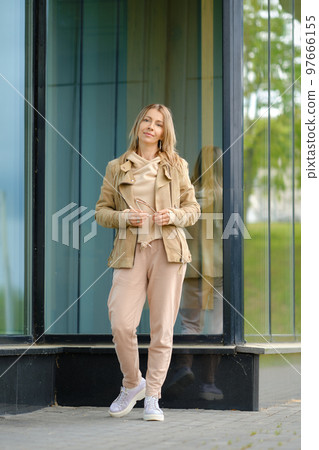woman in track suit stands near the reinforced glass wall of the building 97666155
