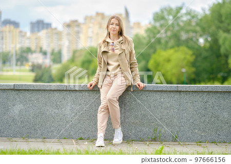 Portrait of sportive middle aged woman sitting on an embankment 97666156