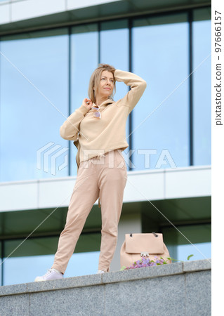 Middle-aged woman looks into the distance and straightens her wind-blown hair 97666157