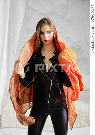 Woman in leather jacket wrapping silk scarf 97666174