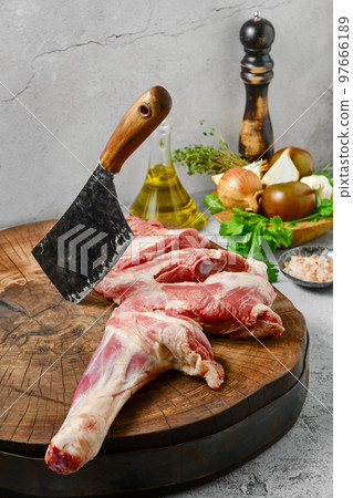 Raw lamb shoulder half cut with butcher's cleaver Raw lamb shoulder half cut with butcher's cleaver 97666189