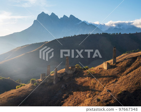 Sunset of Caucasus mountain in the Ingushetia. The medieval battle complex Pyaling is set on the top of the range. Located in the Dzheyrakh region. Russia. 97667348